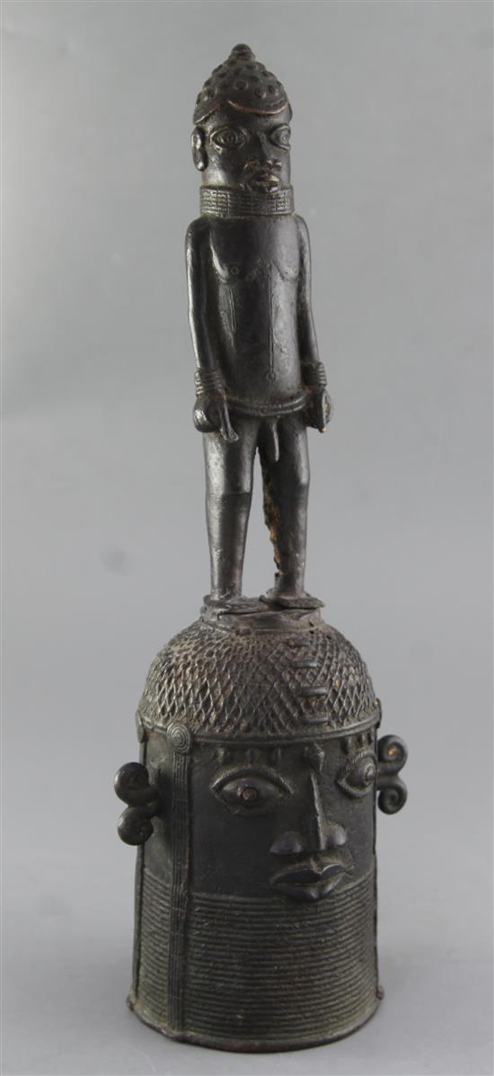 A Benin bronze bell, with standing man handle bearing the head of King Oba, 48cm